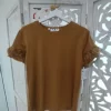 Camiseta marrón con flores de tela en relieve sobre las mangas cortas y corte clásico de caída recta