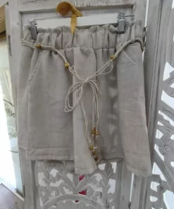 Pantalón corto efecto lino en beige, con cintura alta fruncida, cordón con cuentas de madera y corte holgado.