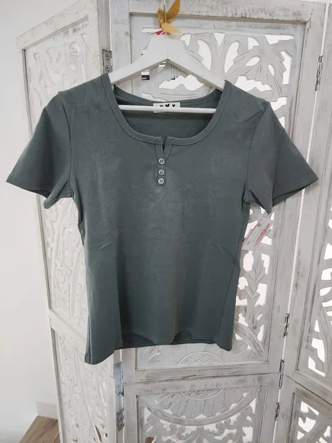 CAMISETA VERDE GRISÁCEO CON DETALLES DE BOTONES M.VG/BO 1 Camiseta verde con botones en tono verde grisáceo, manga corta y escote redondo con abertura