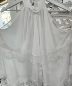 Blusa blanca de puntilla festoneada, sin mangas y con cuello halter fruncido