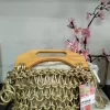 Bolso con asas de madera y cuerpo de trenzados dorados, con asa larga para colgar