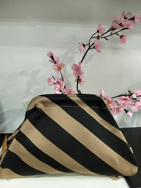 BOLSO DE MANO TIPO CLUTCH ESTAMPADO RAYAS NEGRAS Y BEIGES M.BOL-BEIG 1 Bolso clutch rayas beige y negras con cadena dorada y cierre de boquilla, visto de frente